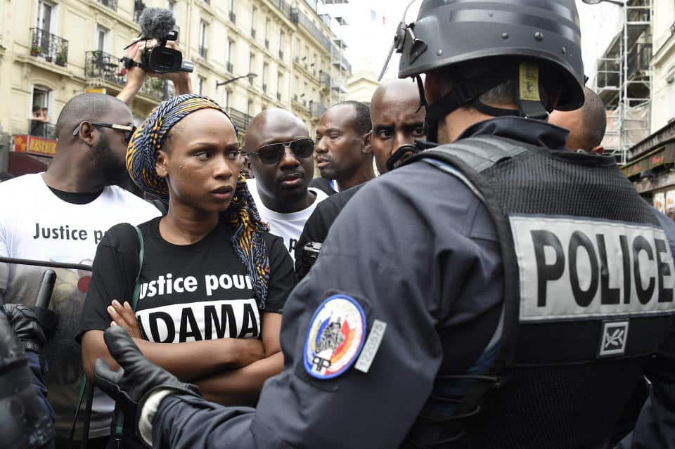 La sœur d’Adama Traore, Assa Traore, face à la police anti-émeute français alors que des manifestants participent à une marche pour protester contre la mort de son frère devant la gare du Nord, à Paris, le 30 juillet 2016. 